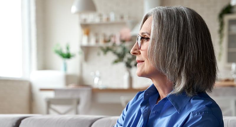 Woman with glasses looking toward the left in her living room